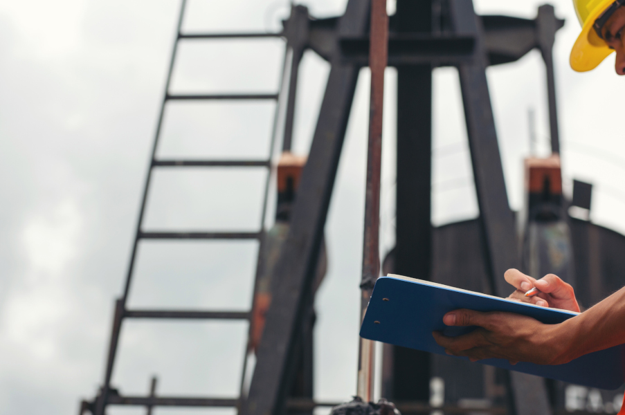 Workers standing and checking beside working oil pumps. Workers standing and checking beside working oil pumps.